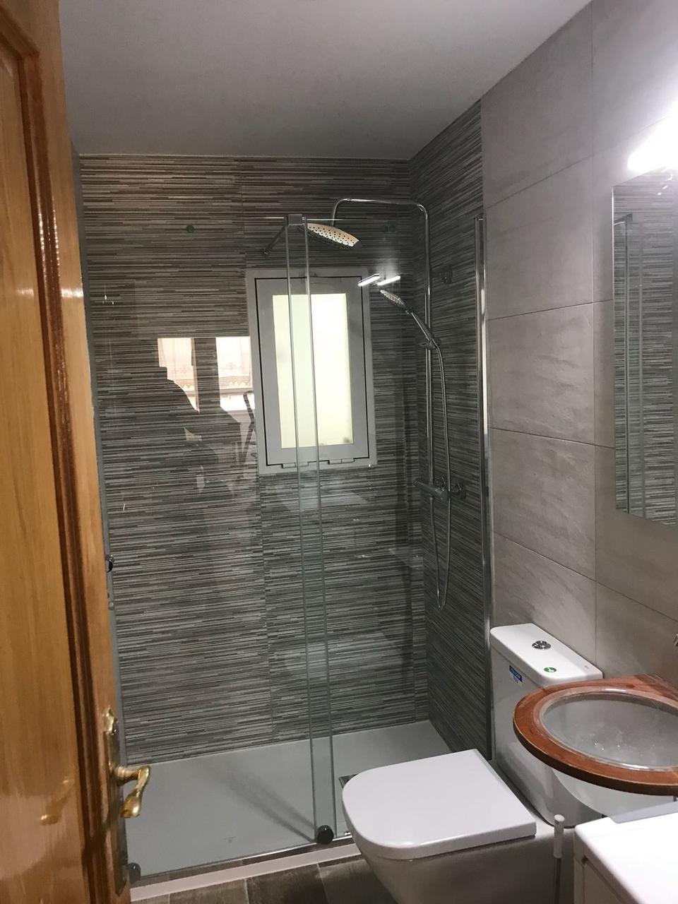 Baño alargado con ducha al fondo y ventana