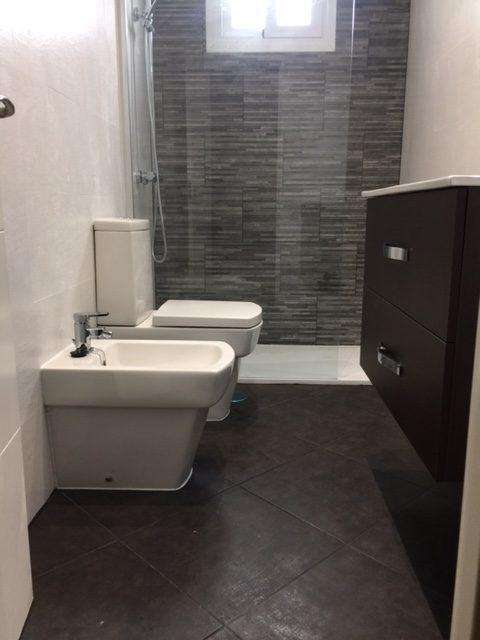 Baño estrecho con inodoro y bidé de líneas rectas