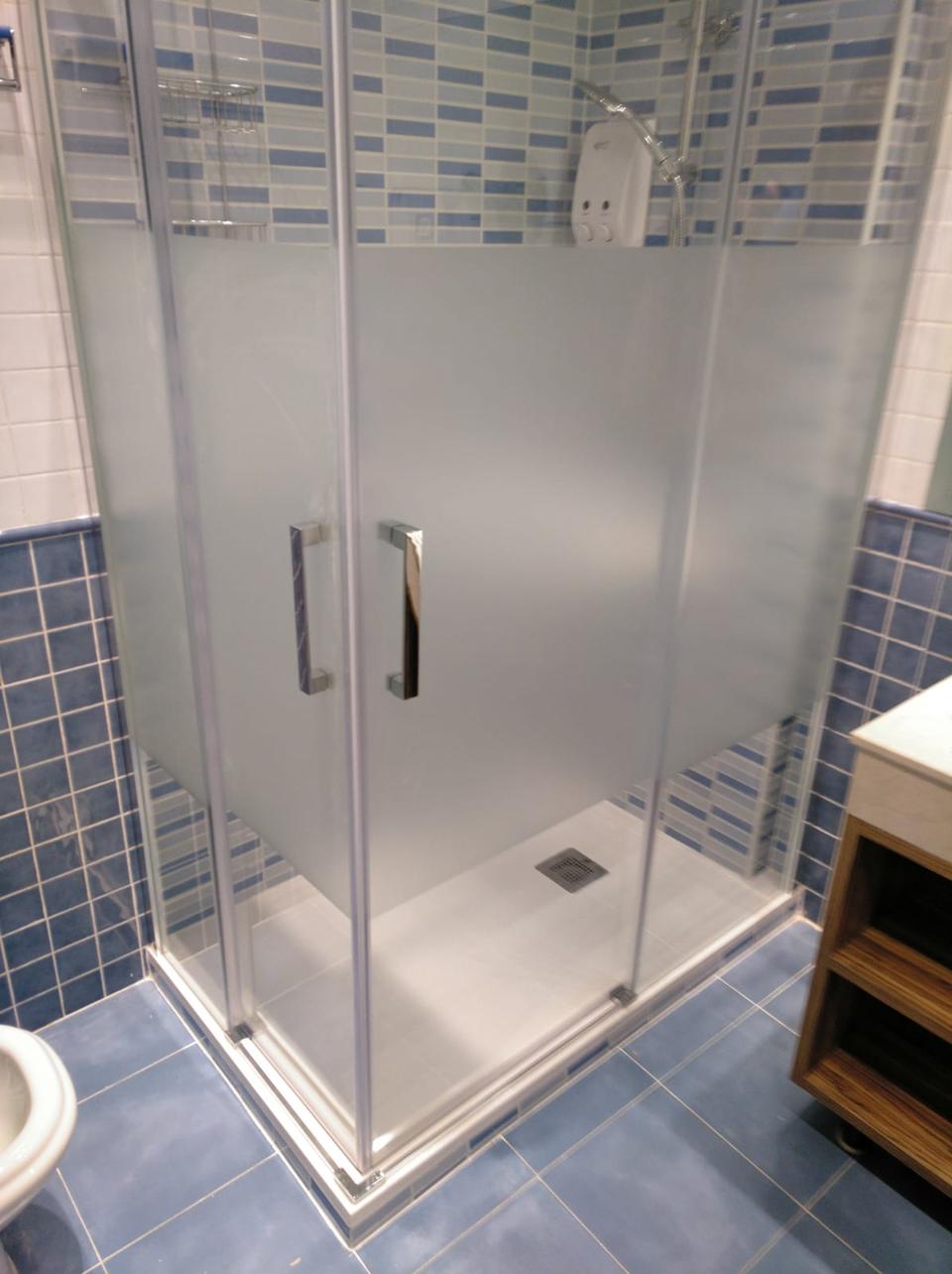 Ducha con mampara de esquina en un baño azul